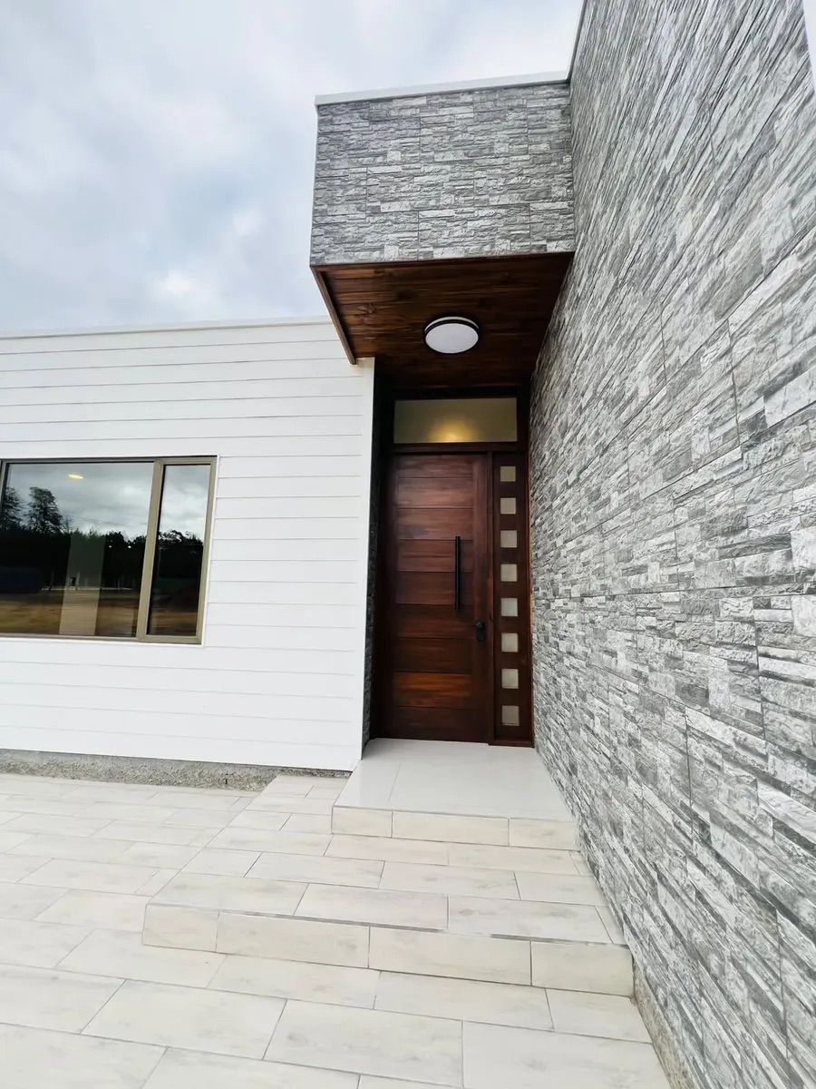 El acceso principal con la puerta de madera y el muro de piedra — Parcela 1, Parcela con casa nueva