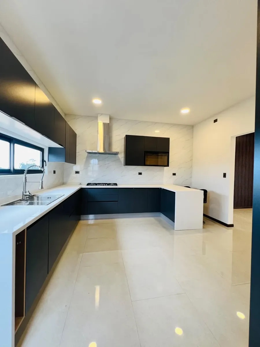 La cocina amplia en U con muebles negros y cubierta blanca — Parcela 1, Parcela con casa nueva
