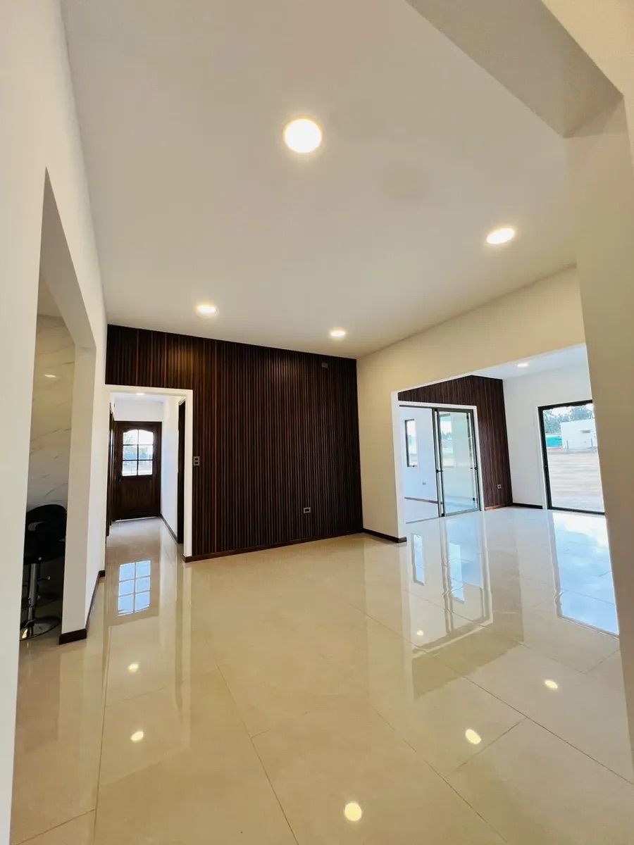 Living y comedor integrados con muro revestido en madera — Parcela 1, Parcela con casa nueva